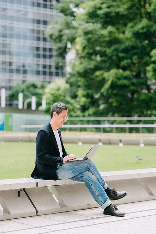 Business man using his laptop in a park.